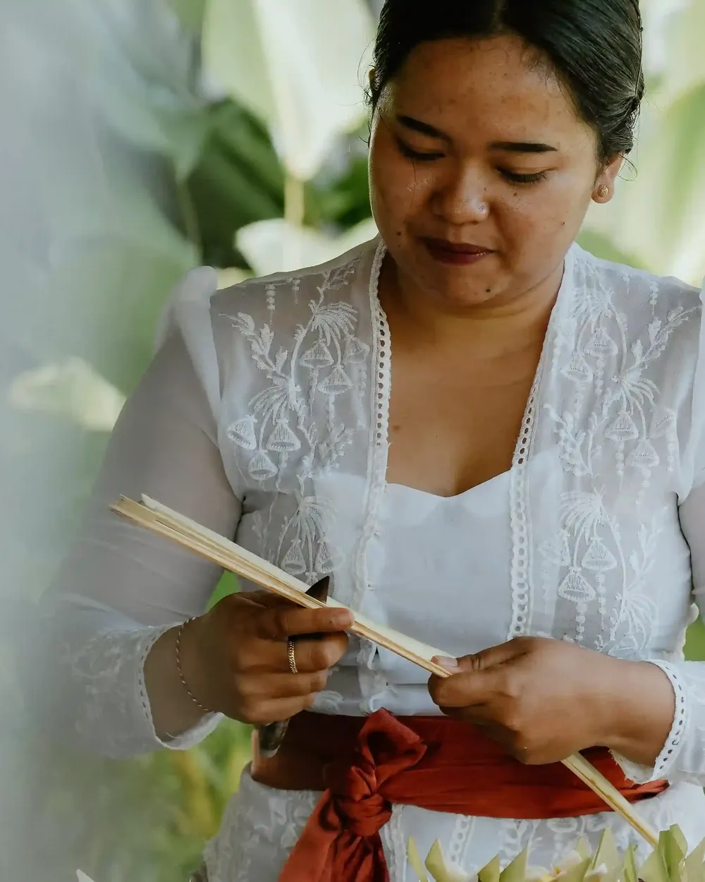 Balinese woman weaving palm leaf by hand