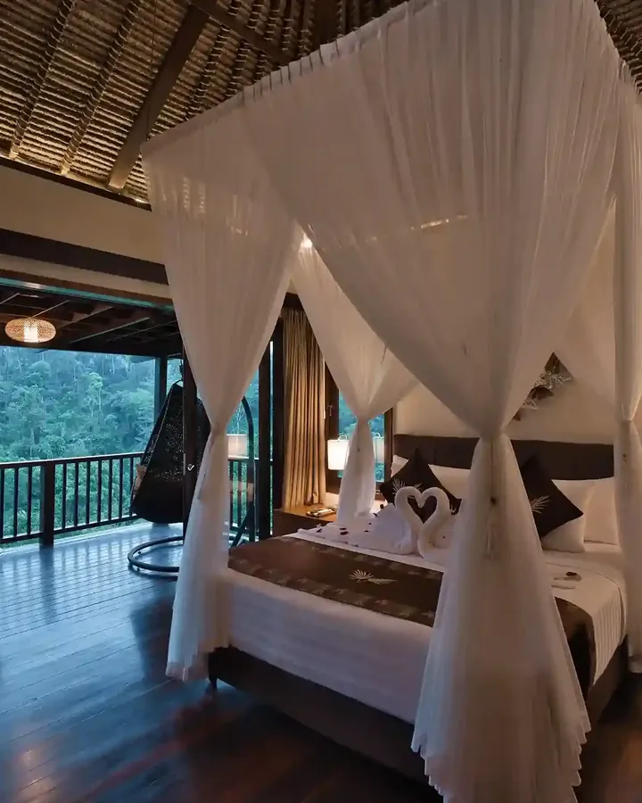 Canopy bed, woven ceiling and hanging woven chair in a jungle resort room near Ubud