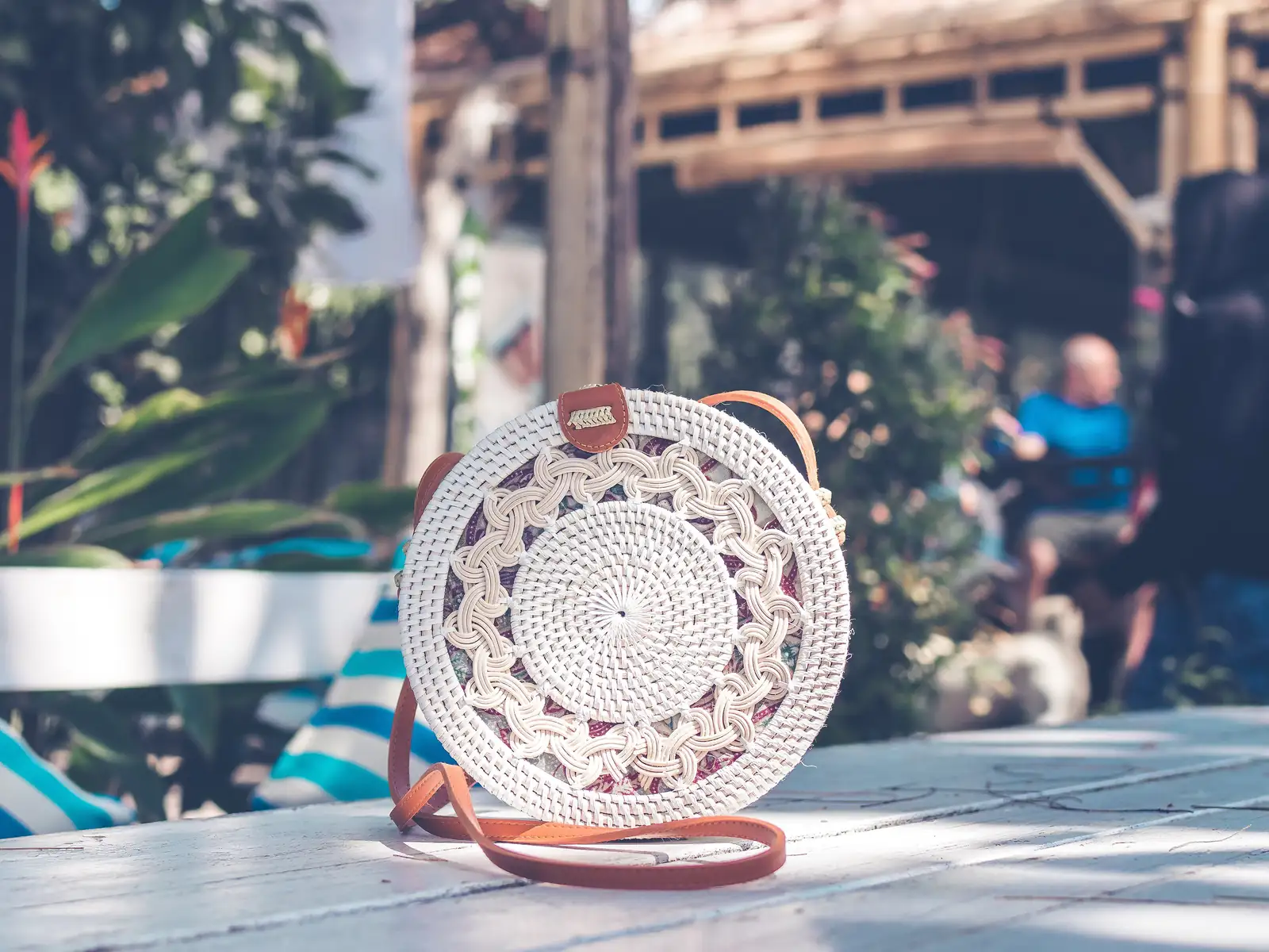 White round rattan bag with a leather strap on a café table in Bali