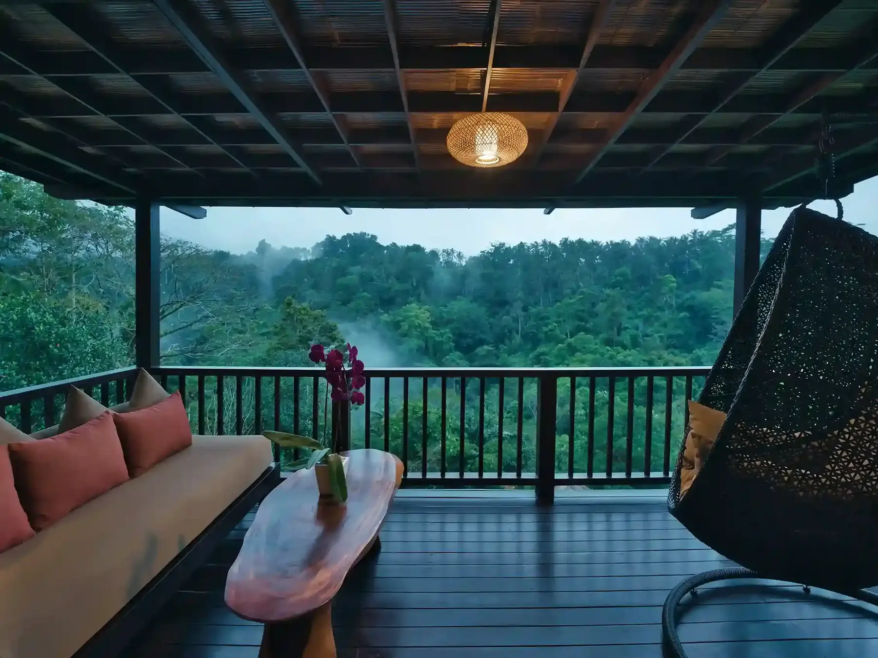 Villa balcony near Ubud with a woven pendant lamp and a hanging woven chair